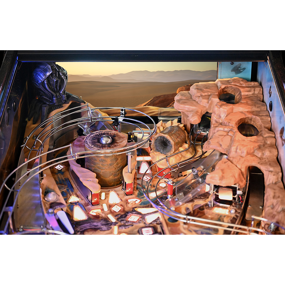 An illuminated pinball playfield, filled with sculpted details